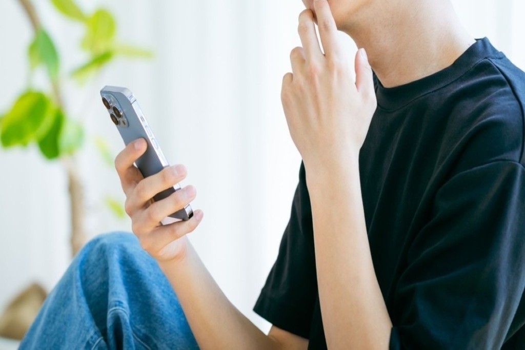 スキマ時間でスマホをチェックする男性